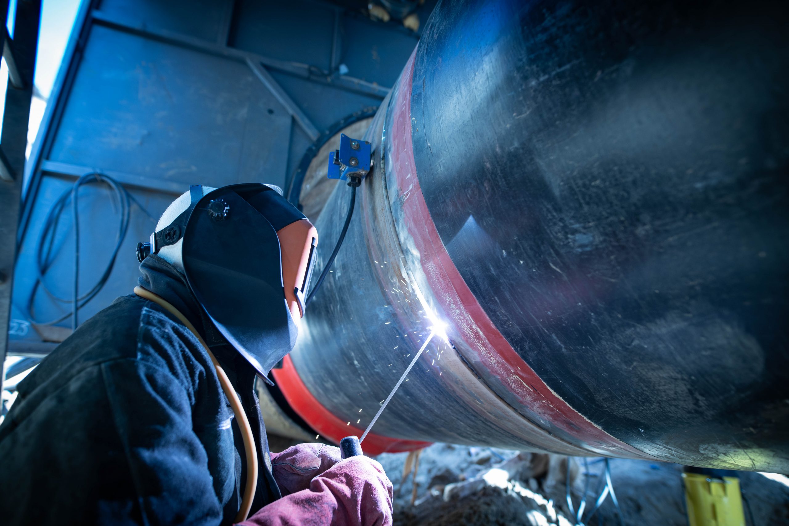 Professional welder welding pipe on a pipeline construction.